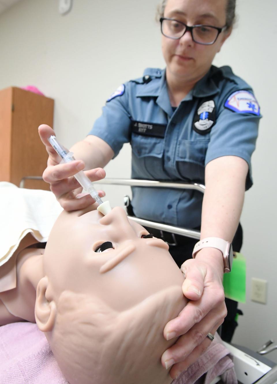 EmergyCare EMT Julie Shotts demonstrates the typical use of Narcan, two squirts in each nostril for a patient who doesn't appear to be breathing, in a training area at EmergyCare in Erie.