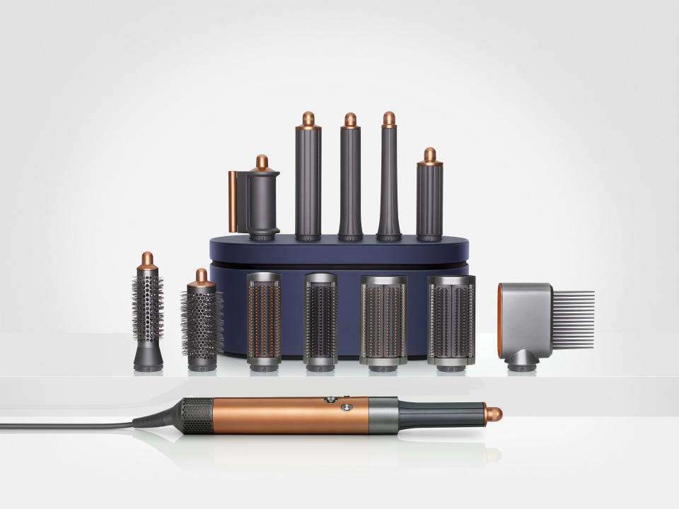 <p>The Dyson Airwrap multi-styler 2022 in front of a neatly arranged set of attachments.</p>
