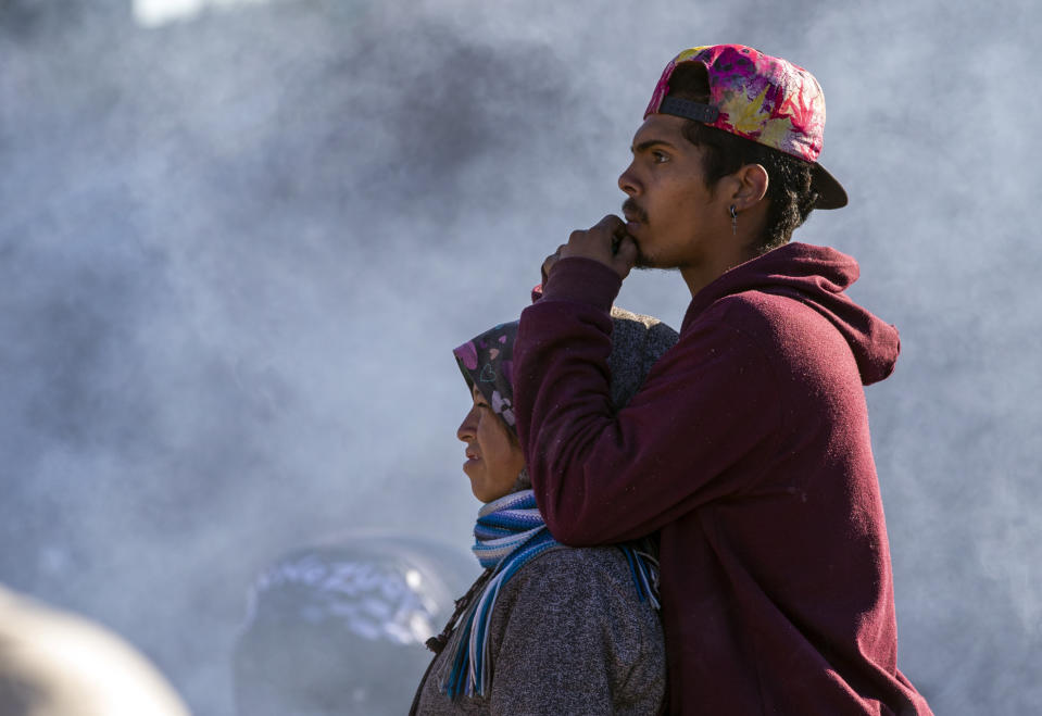 A migrant couple looks towards the border fence trying to decide whether or not to cross the Rio Grande River in their attempt to enter into El Paso, Texas from Ciudad Juarez, Mexico, Wednesday, Dec. 21, 2022. Thousands of migrants gathered along the Mexican side of the southern border Wednesday, camping outside or packing into shelters as they waited for the U.S. Supreme Court to decide whether and when to lift pandemic-era restrictions that have prevented many from seeking asylum. (AP Photo/Andres Leighton)