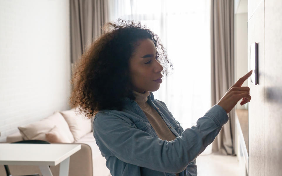 Woman adjusting the temperature on her home thermostat