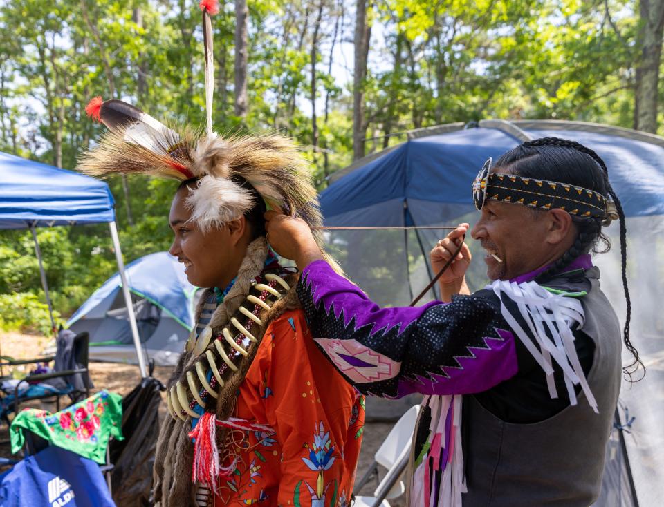 Urie Ridgeway is helping his nephew, Jesse Gould, get ready before the opening ceremony starts at the Wampanoag Powwow Grounds in Mashpee on Friday. Jesse Gould had been dancing for the past 15 years while his uncle, Urie Ridgeway had been dancing for 40 years. 
Sophie Proe/Cape Cod Times