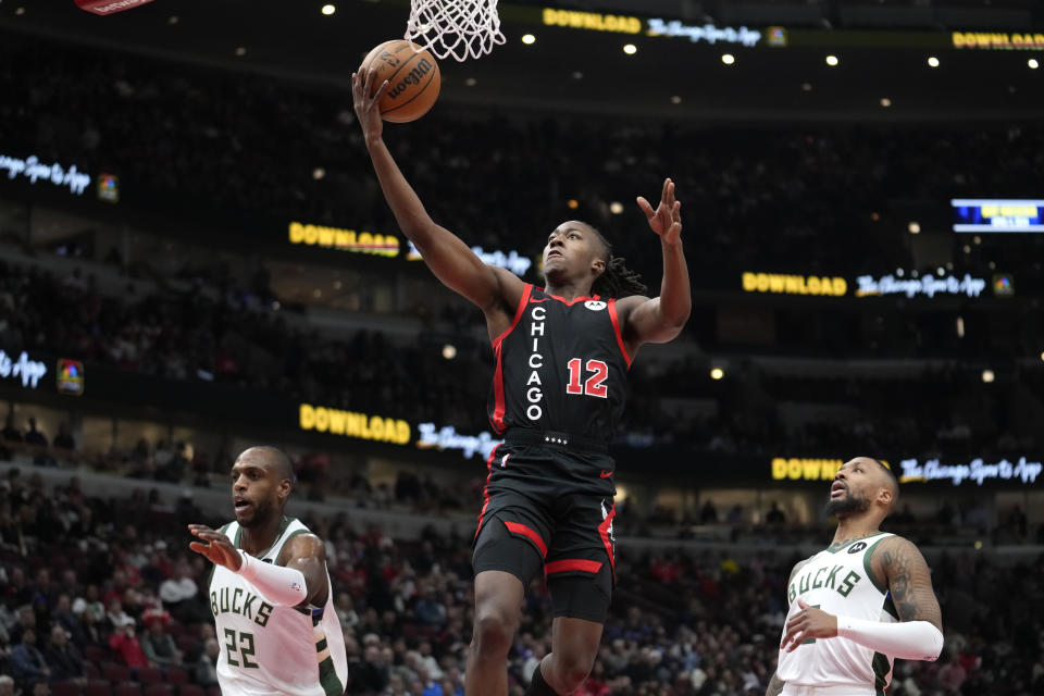 Chicago Bulls' Ayo Dosunmu drives to the basket between Milwaukee Bucks' Khris Middleton (22) and Damian Lillard during the first half of an NBA basketball game, Thursday, Nov. 30, 2023, in Chicago. (AP Photo/Charles Rex Arbogast)