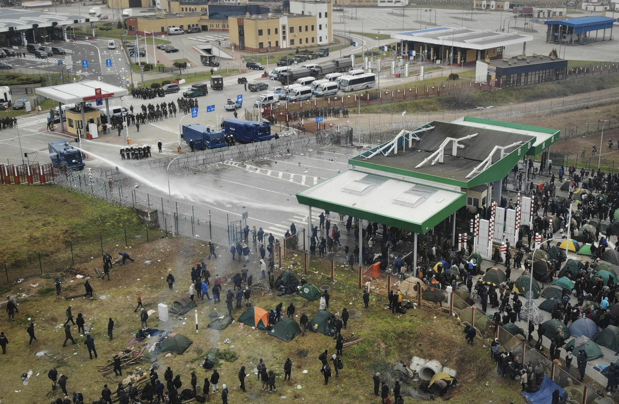 In this image taken with a drone Polish servicemen use a water cannon during clashes between migrants and Polish border guards at the Belarus-Poland border near Grodno, Belarus, on Tuesday, Nov. 16, 2021. Polish border forces say they were attacked with stones by migrants at the border with Belarus and responded with a water cannon. The Border Guard agency posted video on Twitter showing the water cannon being directed across the border at a group of migrants in a makeshift camp. (Leonid Shcheglov/BelTA via AP)