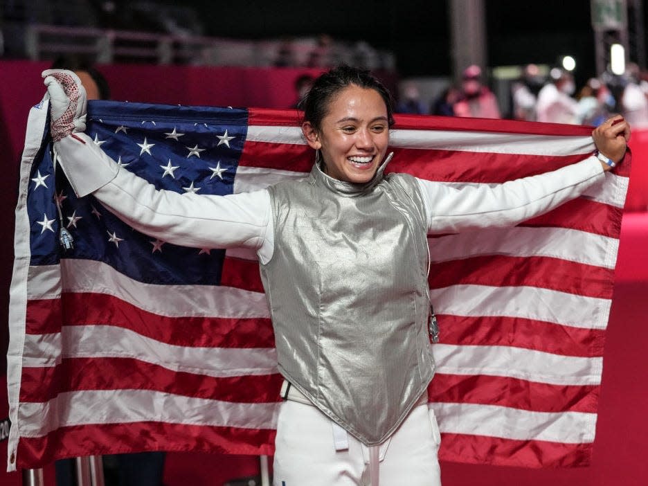 Lee Kiefer holds an American flag after winning a gold medal in fencing at the Tokyo Olympics