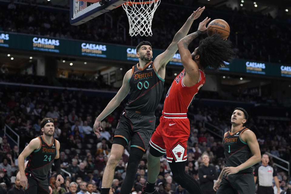 Washington Wizards forward Tristan Vukcevic (00) blocks a shot by Chicago Bulls guard Coby White, center right, during the first half of an NBA basketball game Friday, April 12, 2024, in Washington. (AP Photo/Mark Schiefelbein)