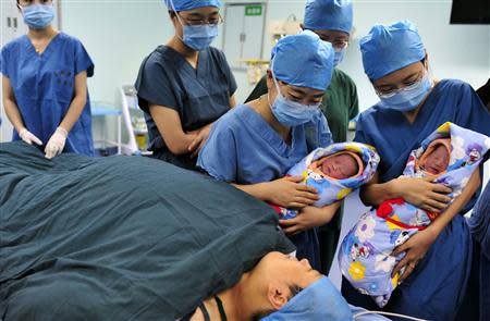 Nurses show a pair of fraternal twins to their mother (bottom) after they were born at the IVF centre of a hospital in Xi'an, Shaanxi province August 16, 2012. BREUTERS/Stringer