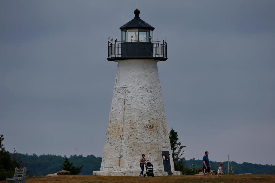A young family has some fun in front of the Ned's Point lighthouse in Mattapoisett.