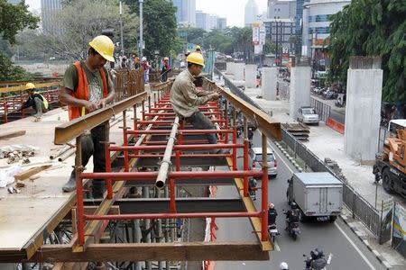 Construction workers are seen on a section of an elevated highway under construction in Jakarta December 2, 2015. REUTERS/Garry Lotulung