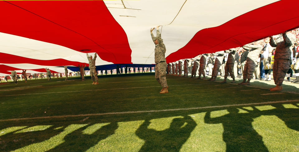 U.S. military servicemen hold a large American flag during ceremonies before the NFL NFC Divisional playoff football game between the New Orleans Saints and the San Francisco 49ers in San Francisco, California, January 14, 2012. REUTERS/Robert Galbraith (UNITED STATES  - Tags: SPORT FOOTBALL)