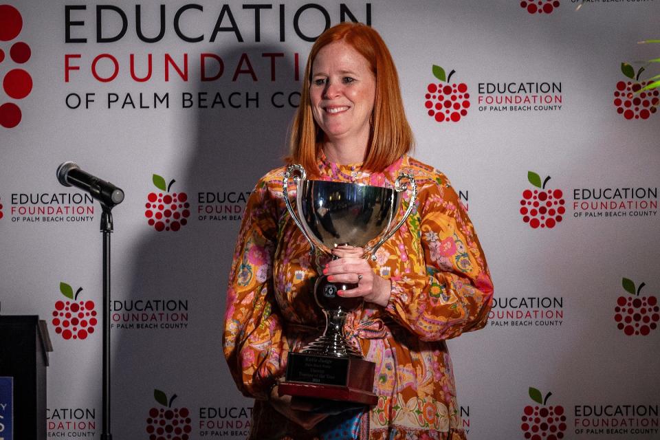 Palm Beach Public teacher Katie Judge holds her trophy for winning Teacher of the Year.