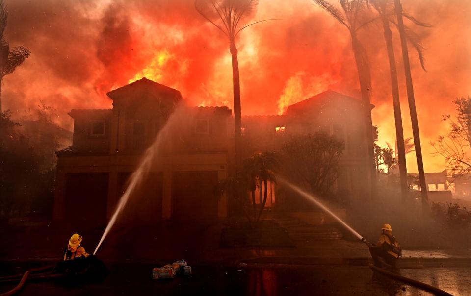 Firefighters hose down a home