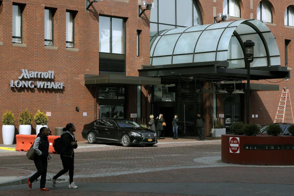 FILE - In this March 11, 2020 file photo, people walk outside the Marriott Long Wharf hotel in Boston. Marriott hotels will require guests to wear masks in lobbies and other public spaces starting July 27. The Bethesda, Maryland-based hotel giant has required employees to wear masks for several months. But in a video message released Monday, July 20 CEO Arne Sorenson said the mandate is being extended to guests. (AP Photo/Steven Senne, File)