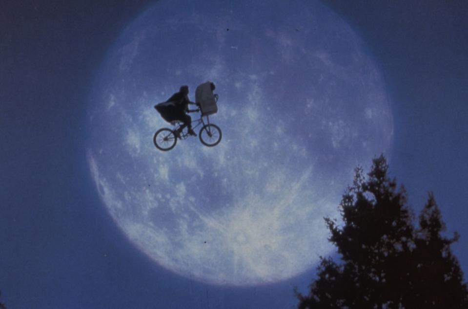 E.T. nach Hause telefonieren - aber erst einmal eine Runde fliegen! Elliott (Henry Thomas) und E.T. auf dem fliegenden Fahrrad, im Hintergrund der überdimensionierte Mond und dazu noch die ergreifende Filmmusik von John Williams: Diese legendäre, durch und durch geniale Szene aus Steven Spielbergs Sci-Fi-Blockbuster "E.T. - Der Außerirdische" (1982) verursacht bis heute Gänsehaut. (Bild: Universal)