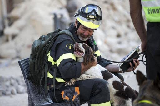 A firefighter cuddles his dog as rescuers continue searching through the rubble in Amatrice, central Italy, Monday, Aug. 29, 2016 after last Wednesday's earthquake. (Massimo Percossi/ANSA via AP)