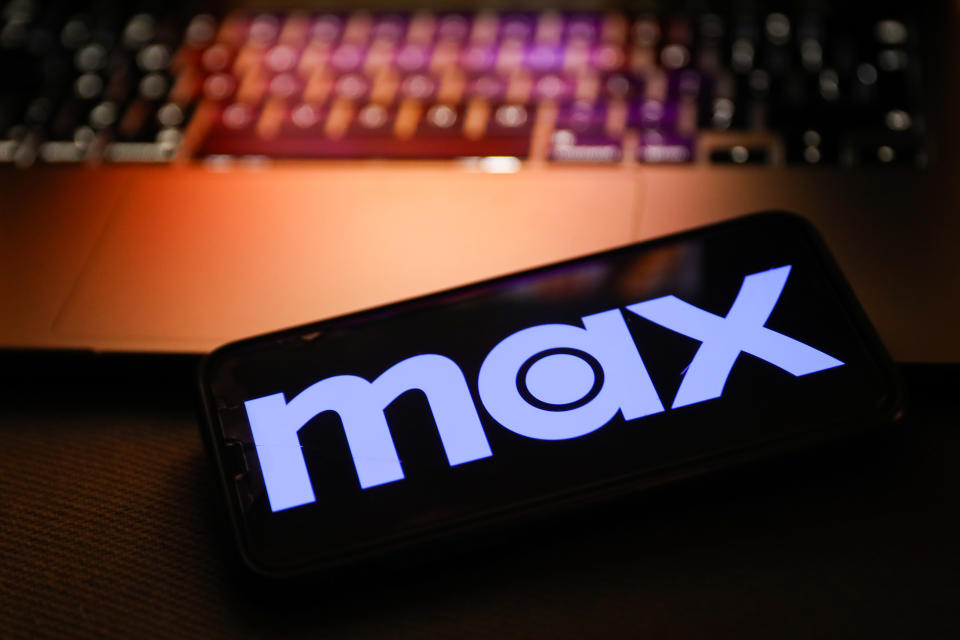 Max logo on a smartphone in front of a laptop keyboard.