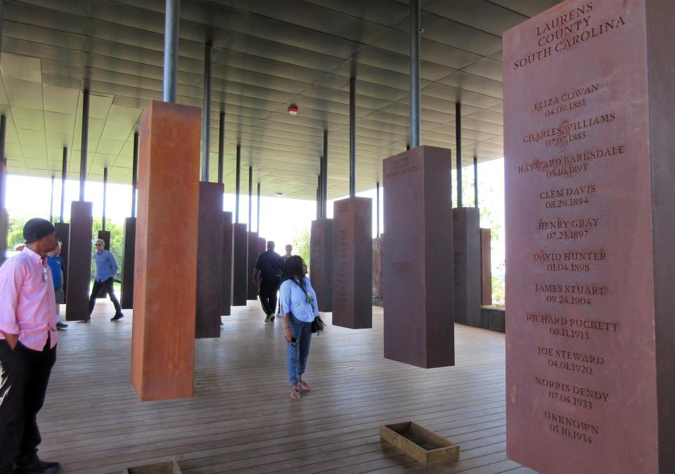 FILE - In this April 28, 2018, file photo, visitors look at markers bearing the names of lynching victims at the National Memorial for Peace and Justice in Montgomery, Ala. Some states have already criminalized the display of nooses, including Louisiana, Virginia, California, New York and Connecticut. Oregon's bill, if passed by the Democrat-controlled Legislature and signed by the Democratic governor, will make intimidation by display of a noose a misdemeanor punishable by up to a year in prison and a $6,250 fine. (AP Photo/Beth J. Harpaz, File)