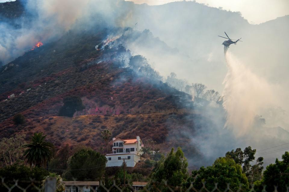 <p>A helicopter drops water to protect a home at the Holy Fire in Lake Elsinore, California, southeast of Los Angeles on Aug. 10, 2018. (Photo: Robyn Beck/AFP/Getty Images) </p>