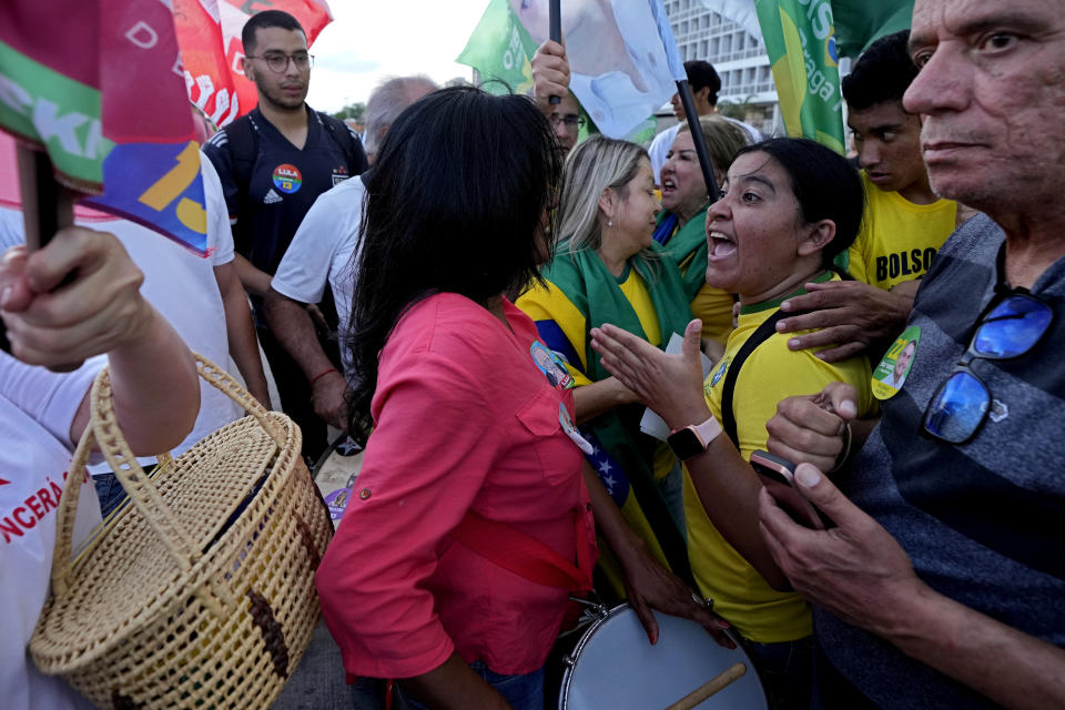 Simpatizantes del presidente brasileño Jair Bolsonaro, que aspira a la reelección, a la derecha, se enfrentan a partidarios del exmandatario Luiz Inácio Lula da SIlva, que desea volver a ser presidente, durante un acto de campaña en una estación de autobuses, el martes 25 de octubre de 2022, en Brasilia. (AP Foto/Eraldo Peres)