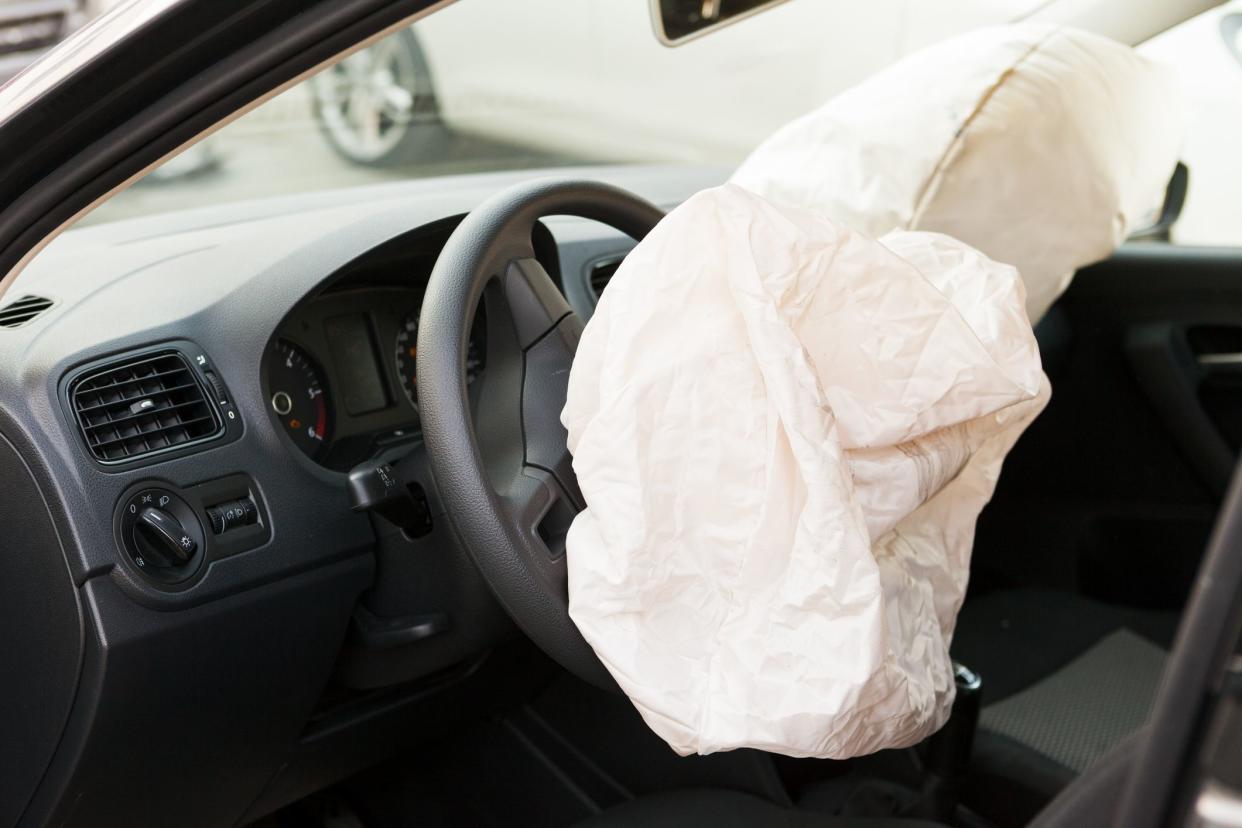 Interior view of 2 deployed airbags, view from driver's side with focus on first airbag and steering.