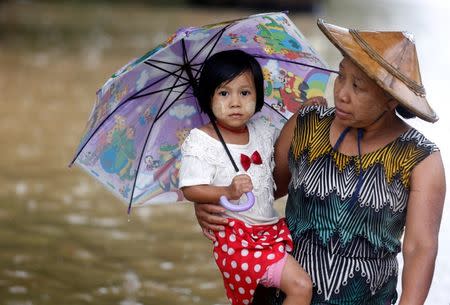 REFILE - QUALITY REPEAT A woman carries her daughter as she walks on a flooded street in Kyaikto township, Mon state, Myanmar July 22, 2017. REUTERS/Soe Zeya Tun