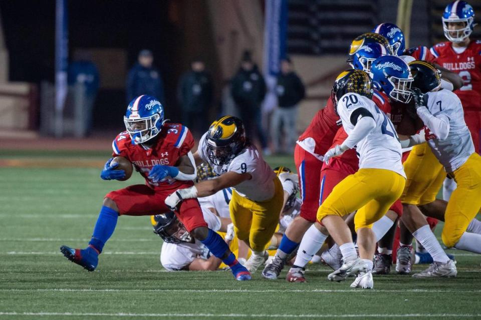 The Folsom Bulldogs’ Donovan Maxey-Parler (34) runs the ball for a first down during the third quarter in the CIF Sac-Joaquin Division I section championship playoff game Friday at Hughes Stadium at Sacramento City College. The Bulldogs won 23-13.