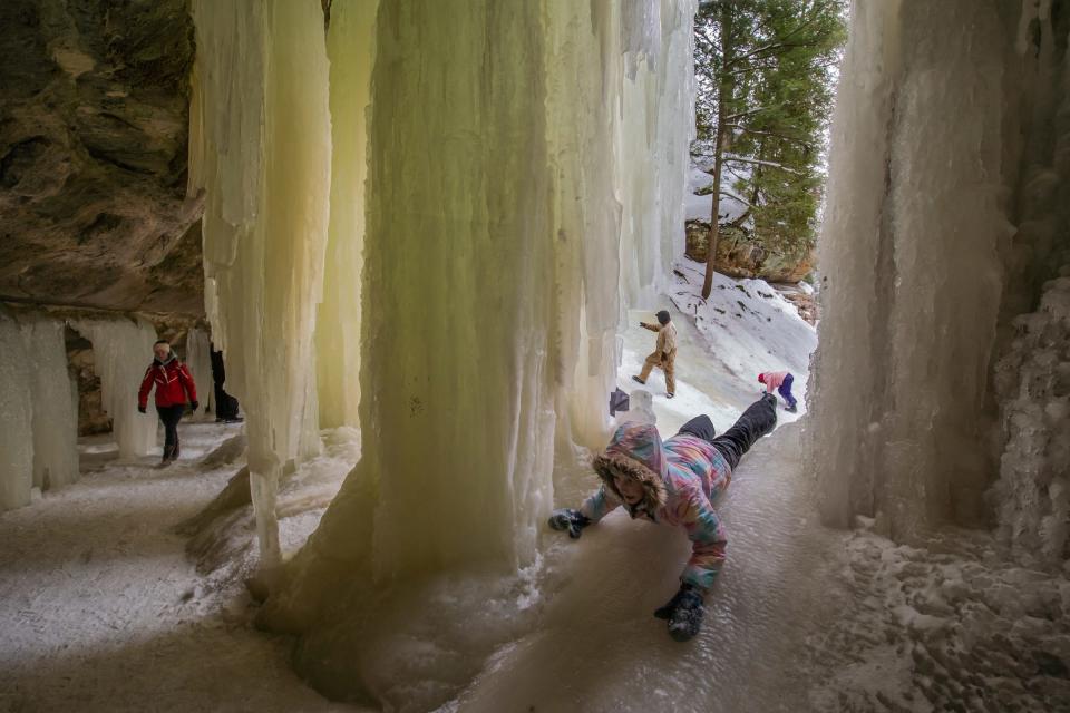 Margot Belonga of St. Ignace slides down an ice mound behind ice formed at the Eben Ice Caves in Eben Junction in February.