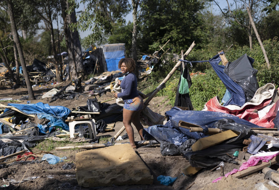 A woman looks to salvage items amid the debris of her torn down home during an eviction at a settlement coined the "First of May Refugee Camp," named for the date people moved on the land designated for a Petrobras refinery, in Itaguai, Rio de Janeiro state, Brazil, Thursday, July 1, 2021, amid the new coronavirus pandemic. (AP Photo/Silvia Izquierdo)