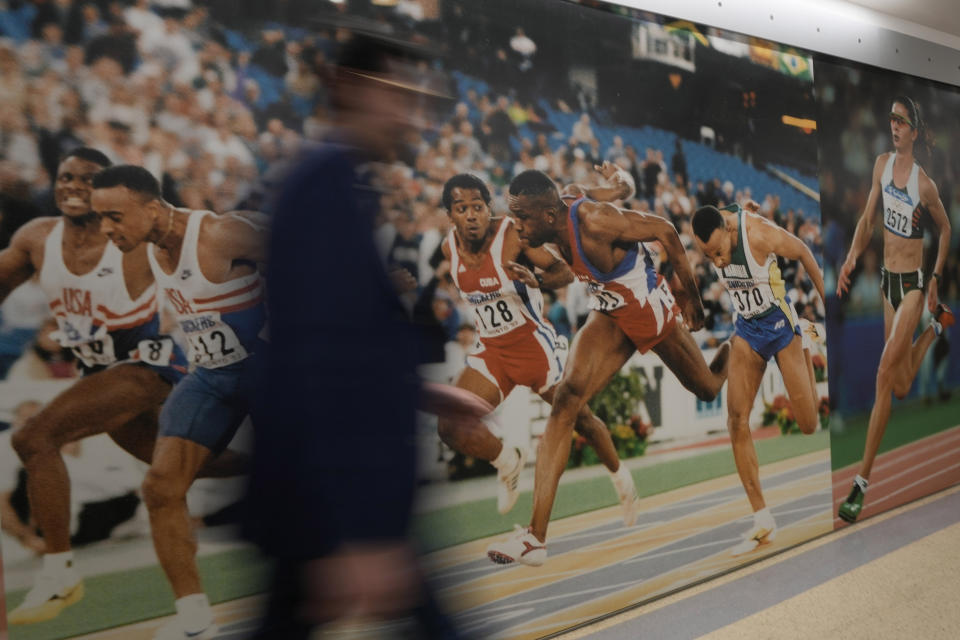 A man walks past a picture of an athletics finish line, at the Mondo factory, in Alba, northern Italy, Wednesday, March 13, 2024. The athletics track for the upcoming Paris Olympics is being produced by the Mondo company at its factory in northern Italy. The track is made in portions, rolled up and then will be transported to the Stade de France, where it will be installed over the next month. (AP Photo/Luca Bruno)