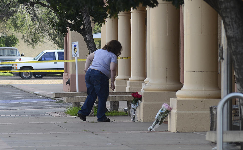 FILE - In this Aug. A woman places flowers at the entrance of the Clovis-Carver Public Library in Clovis, N.M., Tuesday, Aug. 29, 2017, a day after a deadly shooting. Authorities say Nathaniel Ray Jouett, then 17, who opened fire at a rural New Mexico library last year will plead guilty. The August, 2017 shooting killed two librarians and injured four others. District Attorney Andrea Reeb said Tuesday, Oct. 2, 2018 that Jouett has agreed to plead guilty to 30 counts listed in an indictment filed against him, including two counts of first-degree murder. (Adolphe Pierre-Louis/The Albuquerque Journal via AP)