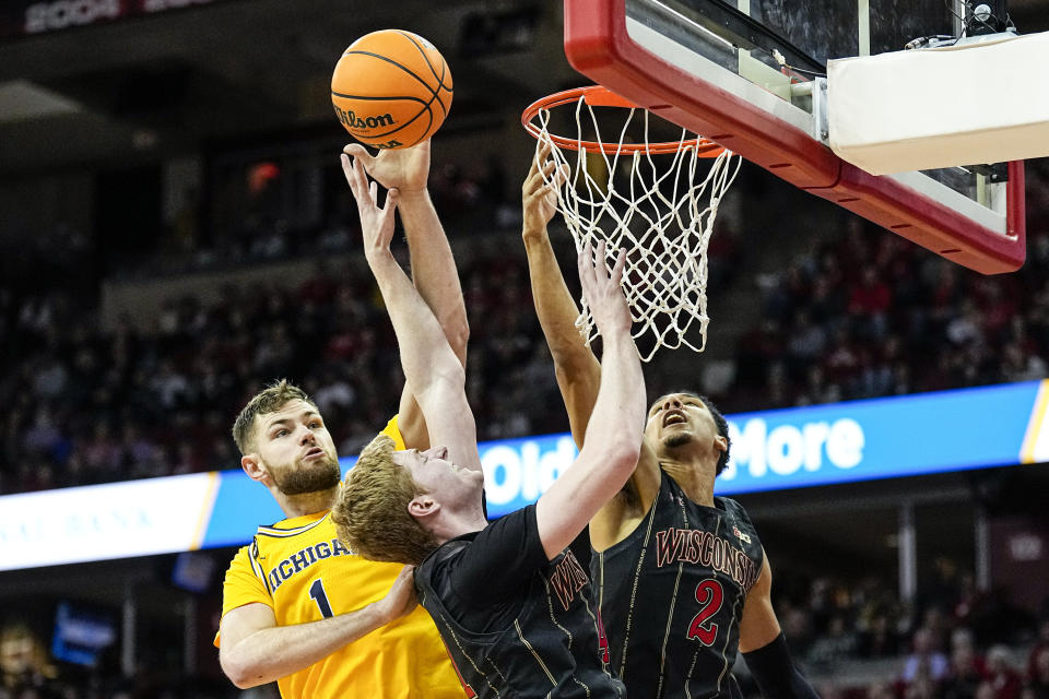 Michigan's Hunter Dickinson (1) blocks a shot by Wisconsin's Steven Crowl and Jordan Davis (2) during the second half of an NCAA college basketball game Tuesday, Feb. 14, 2023, in Madison, Wis. (AP Photo/Andy Manis)