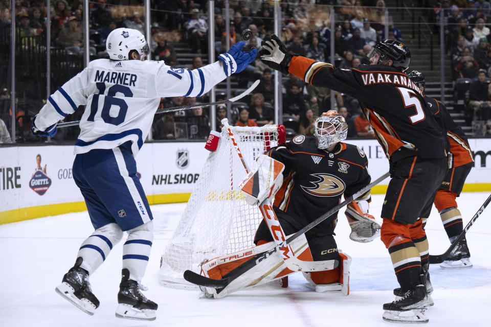 Toronto Maple Leafs right wing Mitchell Marner (16) and Anaheim Ducks defenseman Urho Vaakanainen (5) reach for the puck during the second period of an NHL hockey game Wednesday, Jan. 3, 2024, in Anaheim, Calif. (AP Photo/Kyusung Gong)