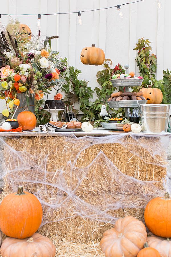 <p>Make a buffet table like Sugar and Charm's by stacking hay and covering it with fake spiderwebs. Then, hang some string lights, surround the spread with pumpkins, add a Halloween-inspired bouquet, and call it a day. </p><p><a class="link " href="https://www.amazon.com/FloraCraft-Decorative-Straw-Bale-Natural/dp/B004XHWKLS/ref=sr_1_4?tag=syn-yahoo-20&ascsubtag=%5Bartid%7C10057.g.2554%5Bsrc%7Cyahoo-us" rel="nofollow noopener" target="_blank" data-ylk="slk:BUY NOW;elm:context_link;itc:0;sec:content-canvas">BUY NOW</a> <strong><em>Decorative Straw Bale, $34</em></strong></p>