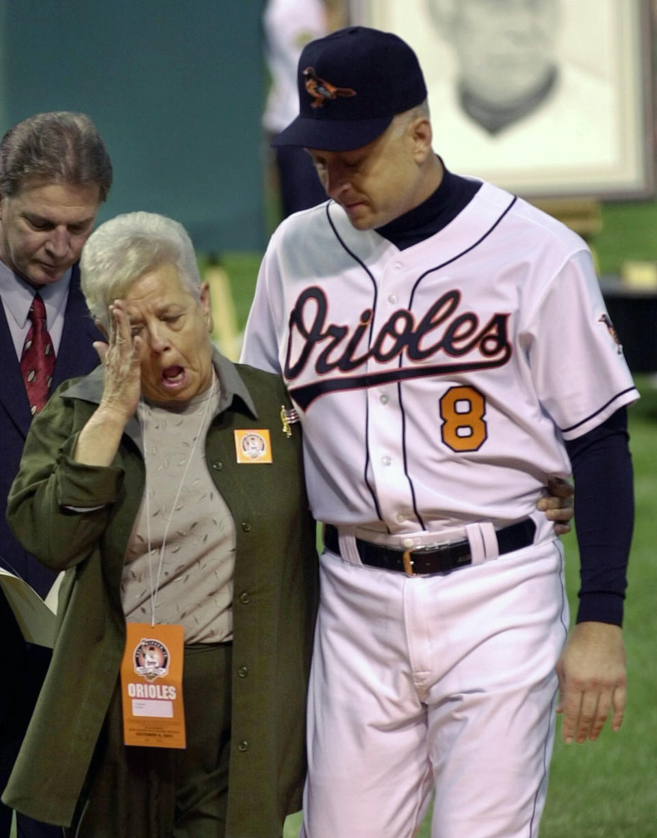 FILE - In this Oct. 6, 2001, file photo, Vi Ripken, mother of Cal Ripken Jr., right, of the Baltimore Orioles, wipes her eye while being escorted by Cal after throwing out the ceremonial first pitch before Cal's final baseball game at Oriole Park at Camden Yards in Baltimore. Vi, matriarch of the famed Orioles family that includes Hall of Fame son Cal Jr. and once the victim of a bizarre kidnapping, has died. She was 82. Family spokesman John Maroon said she died Friday, Feb. 26, 2021, a day before her birthday. (AP Photo/Nick Wass)