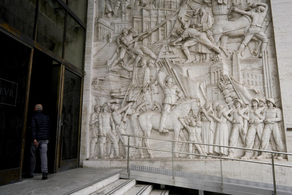 A man enters a building where a marble bas-relief titled "The Story of Rome through its Constructions", made in 1940 by sculptor Publio Morbiducci, shows from top to bottom the history of Rome from its foundation to the fascist period with its dictator Benito Mussolini on a horse, in the EUR neighborhood of Rome, Monday, May 6, 2019. Mussolini transformed Rome’s urban landscape with grand construction projects like EUR, a new city district that was originally designed as celebration of fascism for a world fair in 1942. The fair was canceled due to WWII and construction was halted but resumed after the war. (AP Photo/Andrew Medichini)