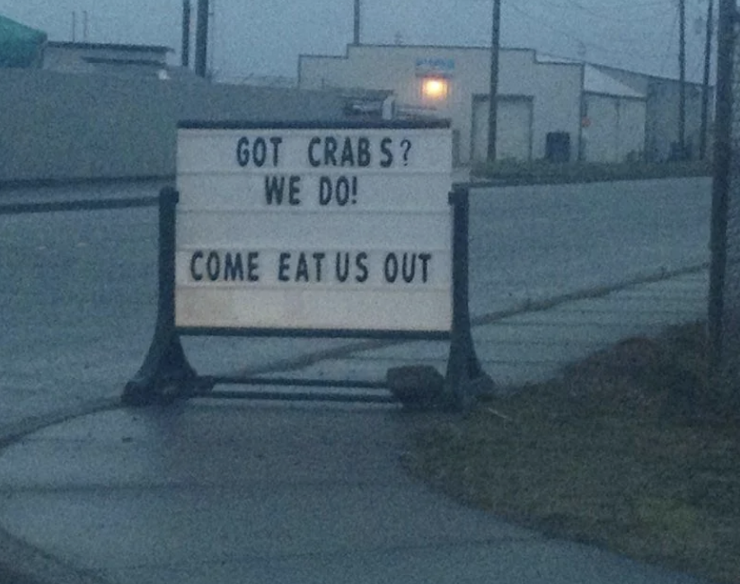 Roadside sign reads "GOT CRAB S? WE DO! COME EAT US OUT," indicating a seafood offering with a spacing error
