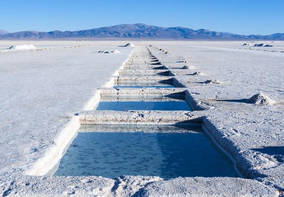 A salt desert showing evaporation ponds with a mountain in the background.