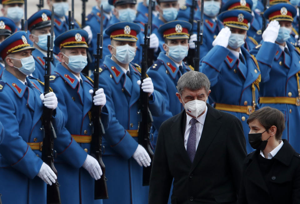 Czech Prime Minister Andrej Babis, centre, reviews the honor guard during a welcome ceremony with his Serbian counterpart Ana Brnabic, right, before their official talks at the Serbia Palace in Belgrade, Serbia, Wednesday, Feb. 10, 2021. Babis is on a one-day official visit to Serbia. (AP Photo/Darko Vojinovic)