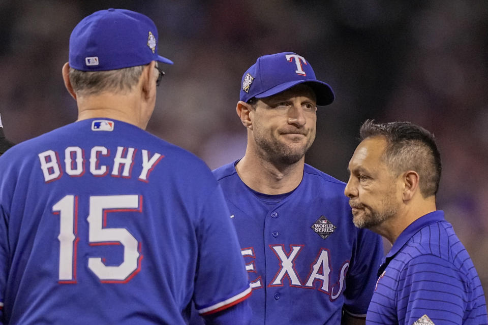 Texas Rangers starting pitcher Max Scherzer leaves the game with head athletic trainer Matt Lucero against the Arizona Diamondbacks during the fourth inning in Game 3 of the baseball World Series Monday, Oct. 30, 2023, in Phoenix. (AP Photo/Brynn Anderson)