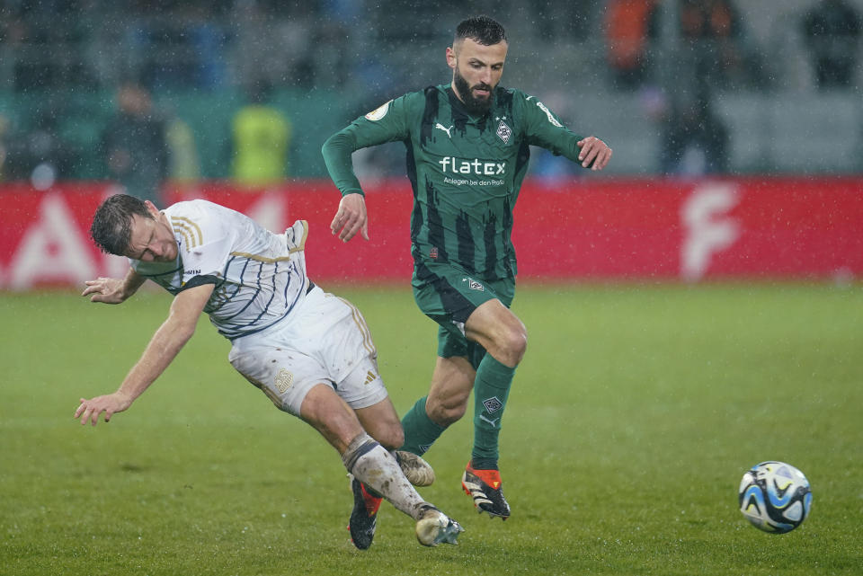 Saarbrucken's Manuel Zeitz, left, and Monchengladbach's Franck Honorat battle for the ball during the German Cup quarterfinal soccer match between FC Saarbrucken and Borussia Monchengladbach at Ludwigspark Stadium, Saarbrucken, Germany, Tuesday March 12, 2024. (Uwe Anspach/dpa via AP)