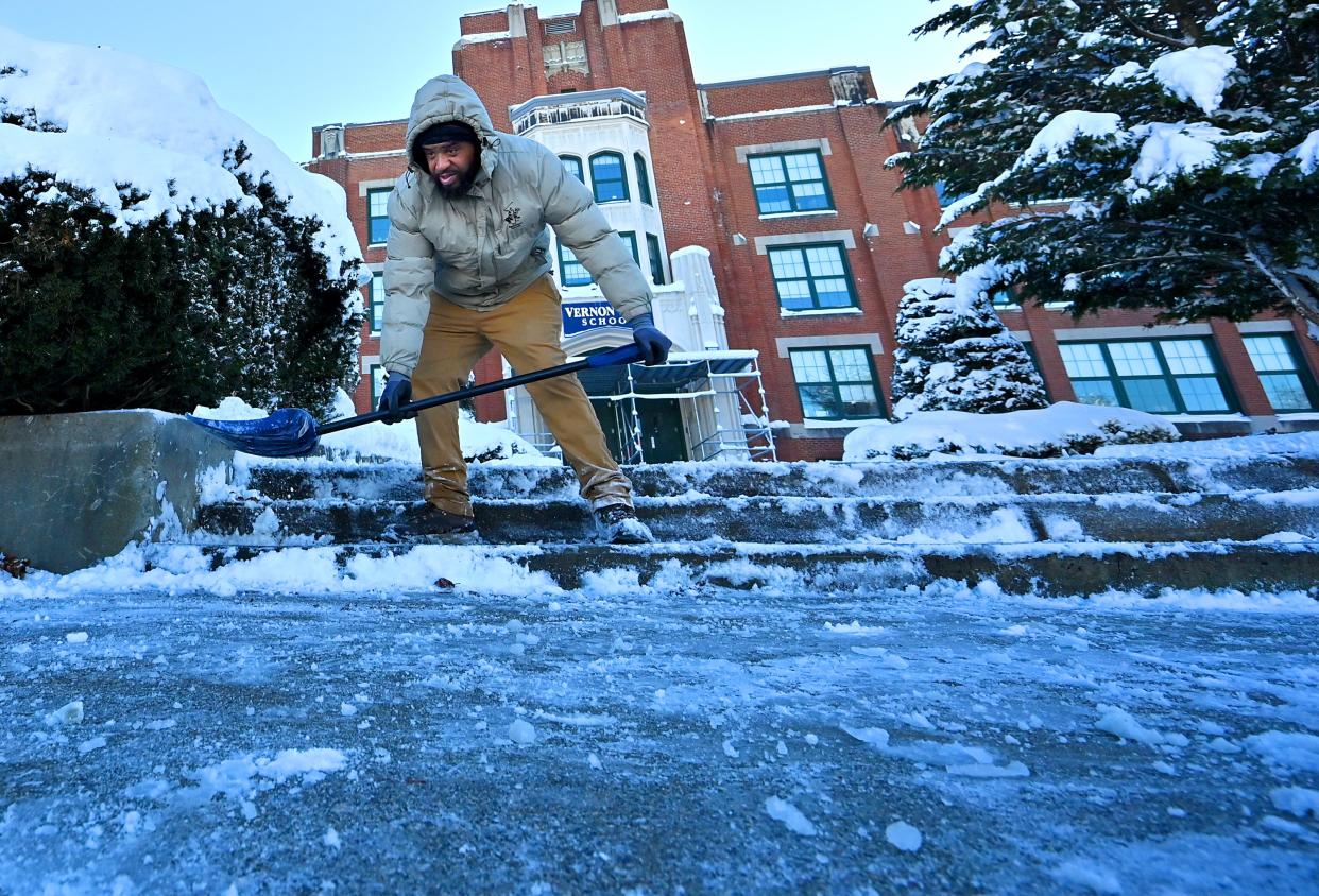 Ricardo Blade, custodian at Vernon Hill School, helps clear snow from the front steps of the school Monday morning.