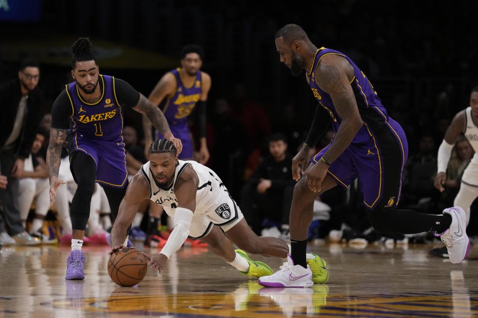 Brooklyn Nets guard Dennis Smith Jr., center, dives for a loose ball against Los Angeles Lakers guard D'Angelo Russell (1) and forward LeBron James (23) during the first half of an NBA basketball game in Los Angeles, Friday, Jan. 19, 2024. (AP Photo/Ashley Landis)