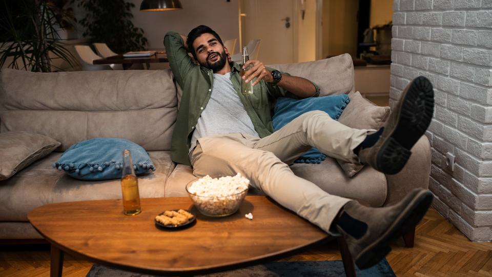 Young man lying on couch watching TV.