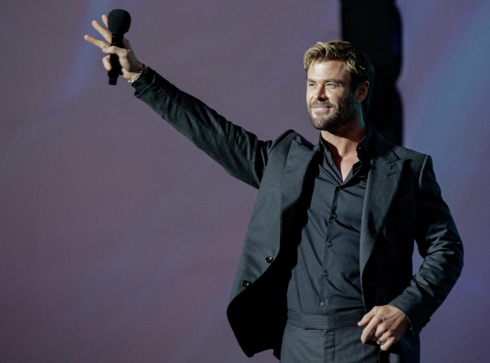 Chris Hemsworth, wearing a black shirt and blazer, on stage at the global Netflix fan event 