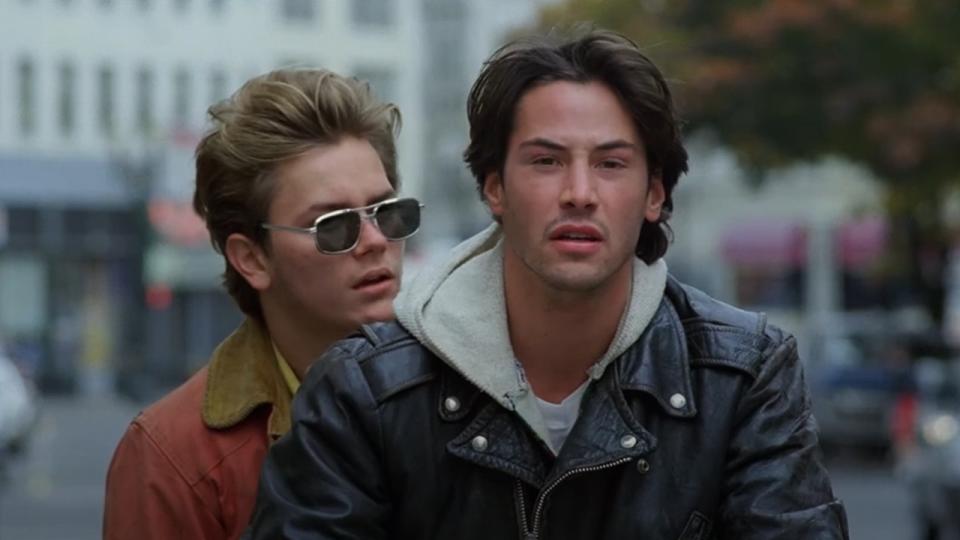 River Phoenix sitting behind Keanu Reeves in My Own Private Idaho.