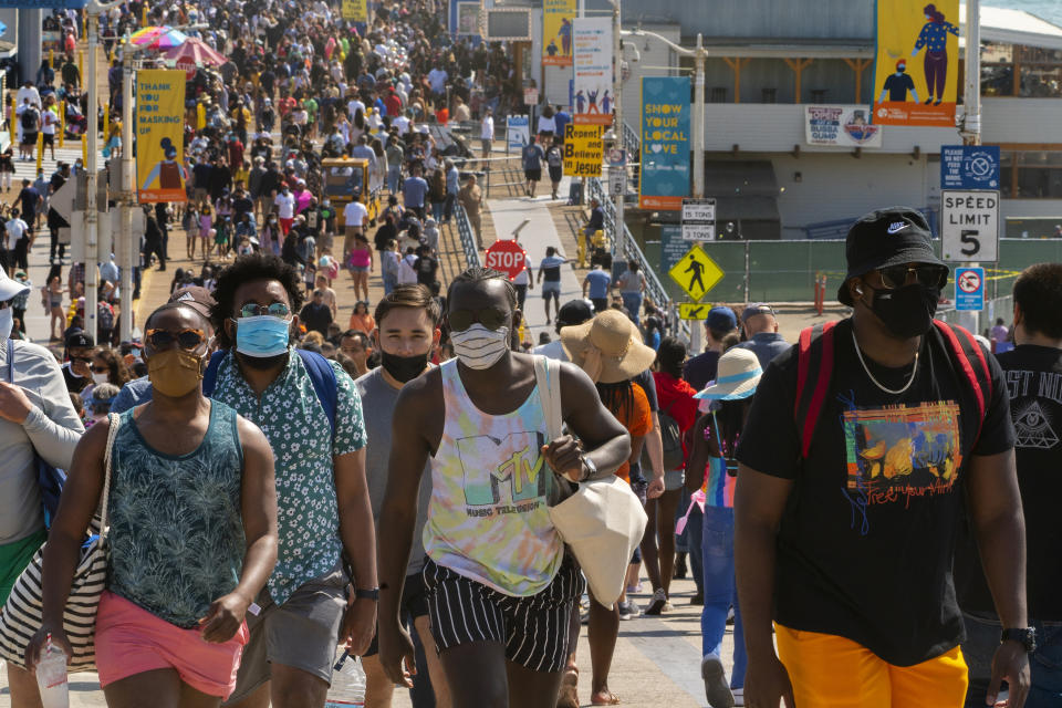 FILE - In this Saturday, May 29, 2021, file photo, people crowd the Santa Monica Pier in Santa Monica, Calif. Californians headed to campgrounds, beaches and restaurants over the long holiday weekend as the state prepared to shed some of its coronavirus rules. (AP Photo/Damian Dovarganes, File)