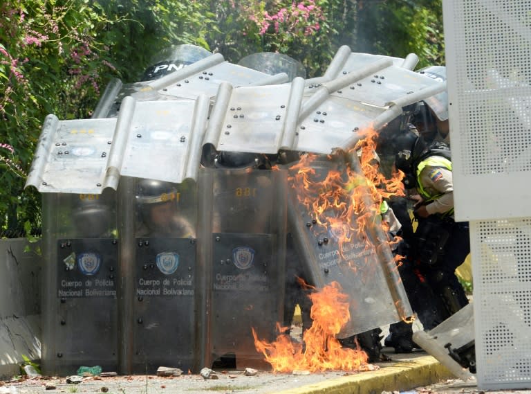 Riot police protect themselves with their shields after students of the Central University of Venezuela threw Molotov cocktails during a protest