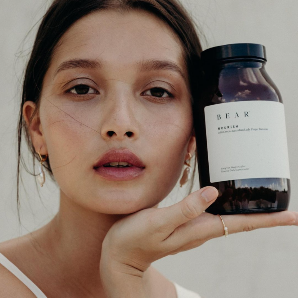 Woman holding a bottle of Australian beauty and wellness brand Bear's Nourish super powder