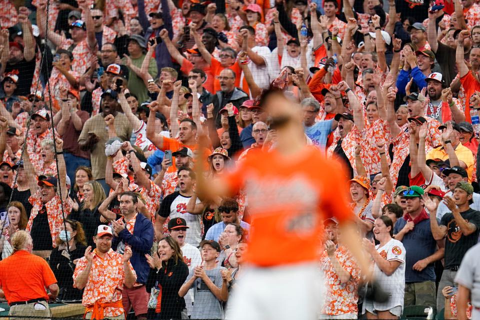 Fans wearing promotional Hawaiian shirts react after the Baltimore Orioles recorded the final out against the Los Angeles Angels during the ninth inning of a baseball game, Saturday, July 9, 2022, in Baltimore. The Orioles won 1-0. (AP Photo/Julio Cortez)