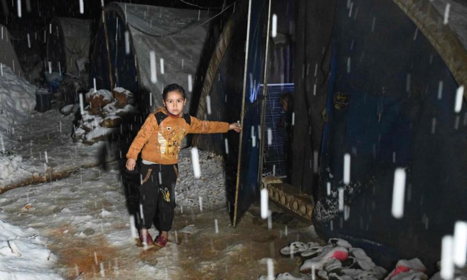 A Syrian girl stands by a tent at a camp for displaced people.