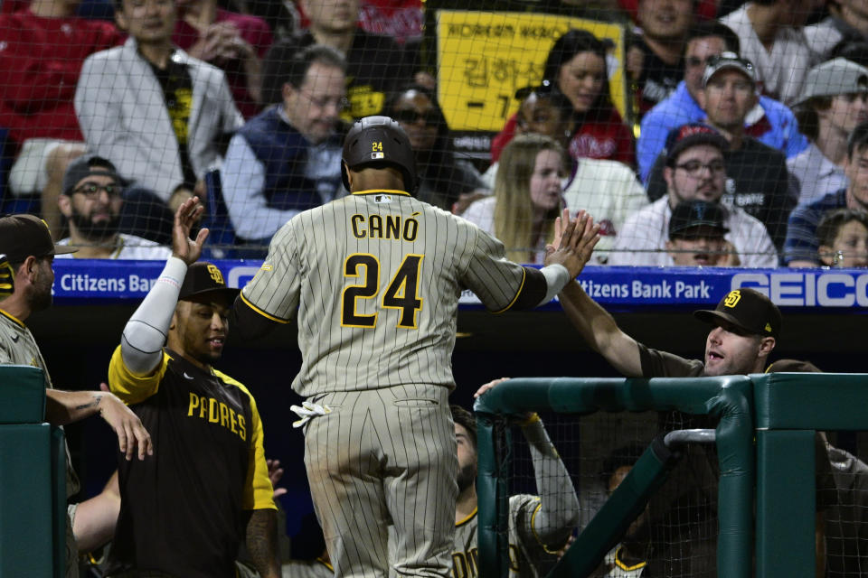 San Diego Padres' Robinson Cano celebrates with teammates after scoring on a hit by Trent Grisham during the seventh inning of a baseball game against the Philadelphia Phillies, Tuesday, May 17, 2022, in Philadelphia. (AP Photo/Derik Hamilton)